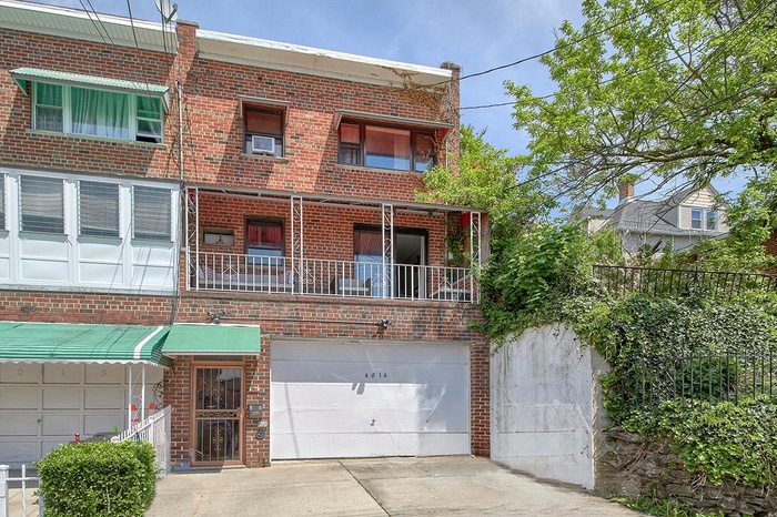 Multi unit property with brick siding, concrete driveway, an attached garage, and a balcony