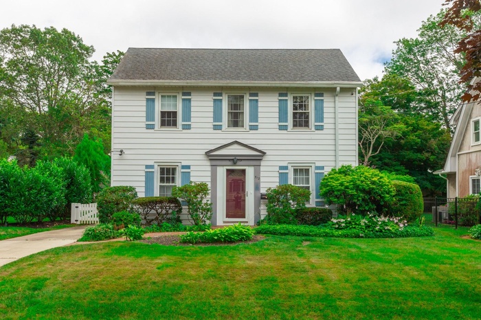 Colonial home featuring roof with shingles