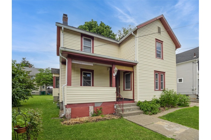 View of front of home with a porch, a chimney, and a front lawn