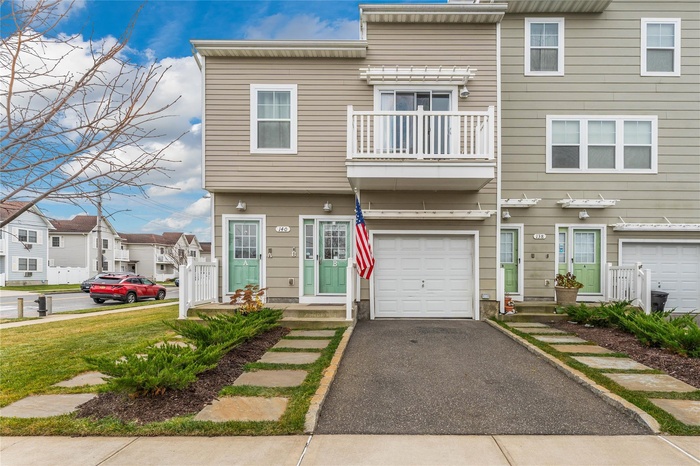 View of front facade featuring a balcony, an attached garage, driveway, and a residential view
