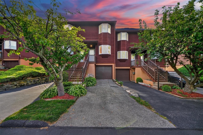 View of front of house featuring stairway, a garage, and driveway
