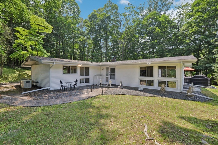 Front of house featuring a lawn, a patio area, and a chimney