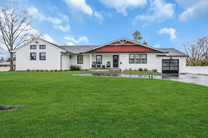 View of front of house with a front yard, an attached garage, driveway, and roof with shingles