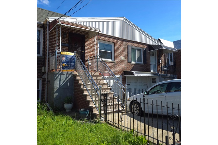 View of front of house with an attached garage, a fenced front yard, brick siding, and driveway