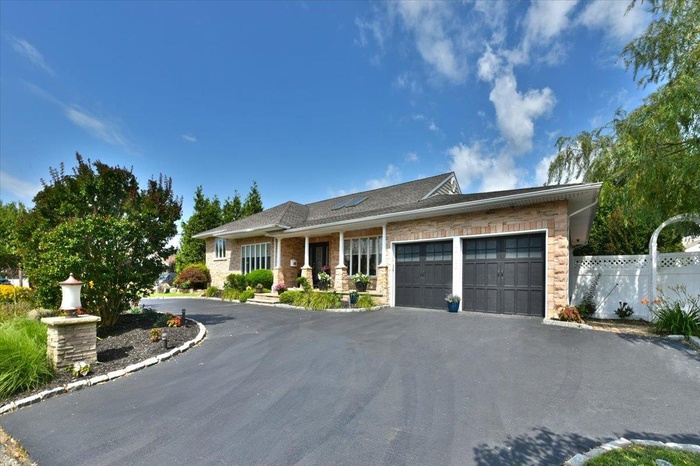 View of front of house with asphalt driveway, a garage, and brick siding