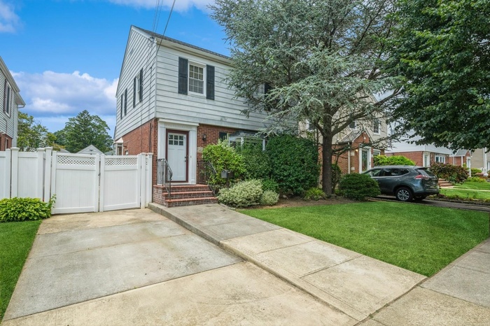 Colonial house featuring brick siding, a gate, and concrete driveway