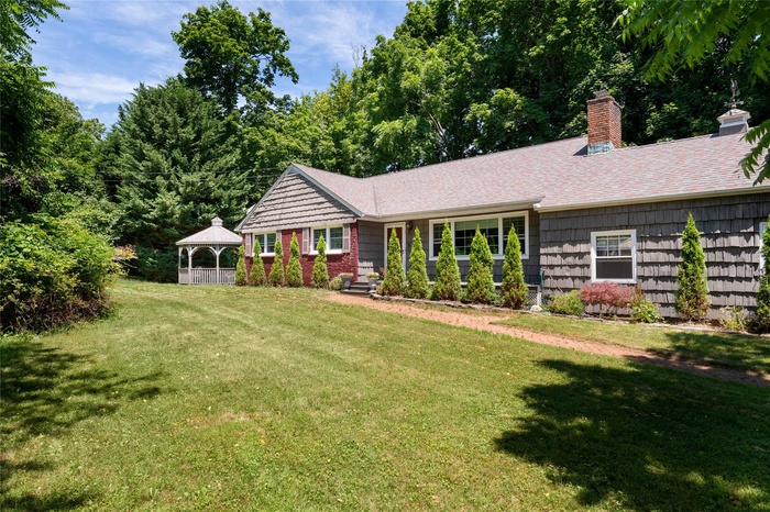 Single story home with a gazebo, a front lawn, and chimney