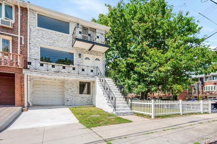 Townhome / multi-family property featuring an attached garage, a balcony, stone siding, and concrete driveway