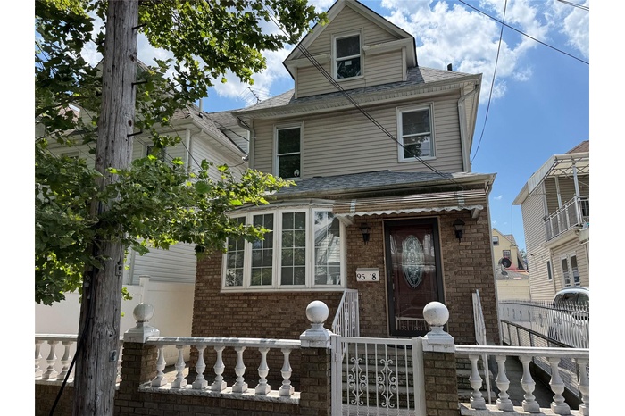 American foursquare style home with a fenced front yard, brick siding, and roof with shingles