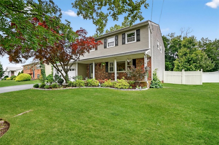 Colonial house with a garage, covered porch, and driveway