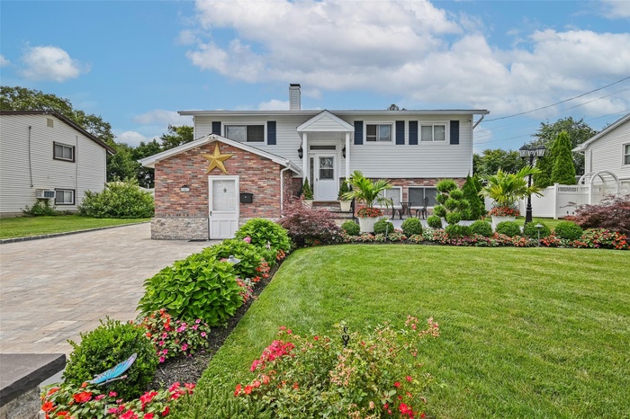 Split foyer home with a chimney, brick siding, and a front yard