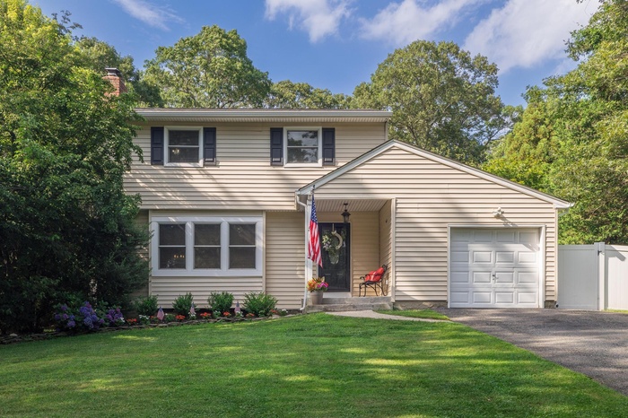 View of front of property featuring an attached garage, asphalt driveway, and a chimney
