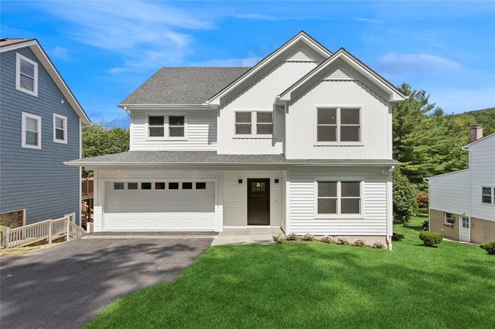 View of front of property featuring a garage, asphalt driveway, roof with shingles, a front lawn, and board and batten siding