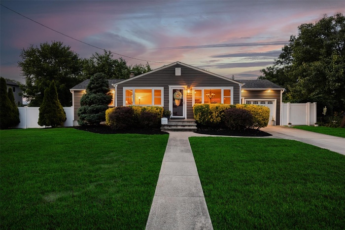 View of front of property featuring a garage, concrete driveway, and roof with shingles