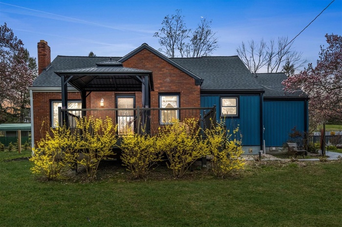 Back of house featuring a shingled roof, a yard, a gazebo, a chimney, and board and batten siding