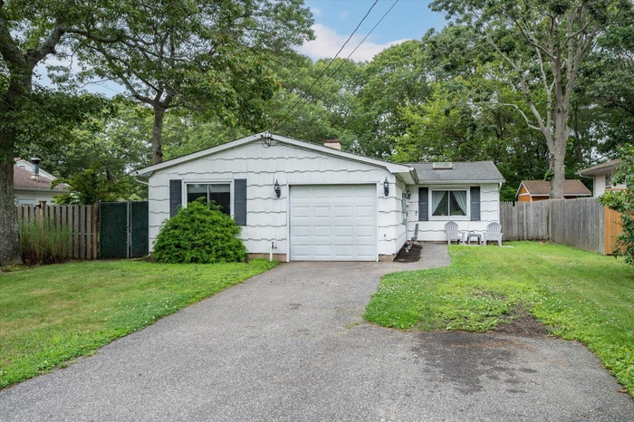View of front of house featuring a garage, a chimney, and asphalt driveway
