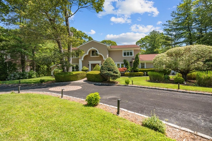 View of front facade with a front lawn and curved driveway