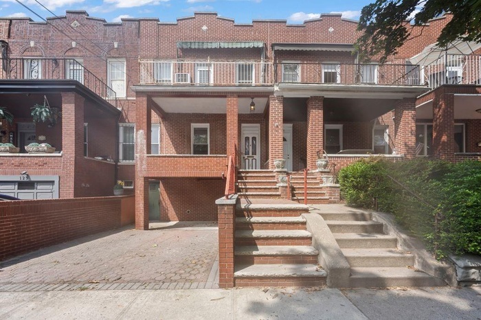 View of front of property with brick siding, stairs, and a porch