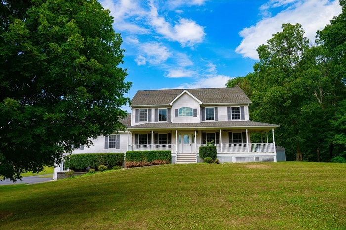 View of front of house with a porch, a front yard, and roof with shingles