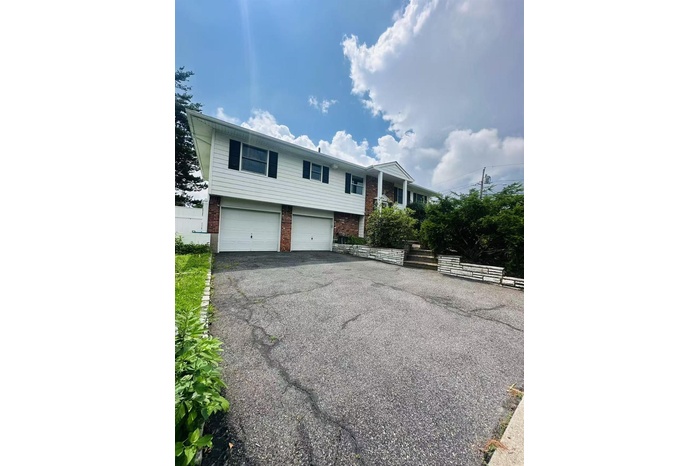 Bi-level home featuring brick siding, driveway, and an attached garage