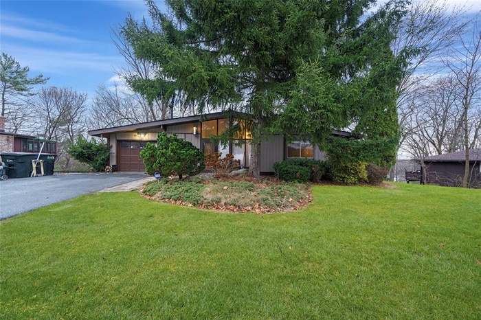 View of front of home featuring asphalt driveway, an attached garage, and a front lawn