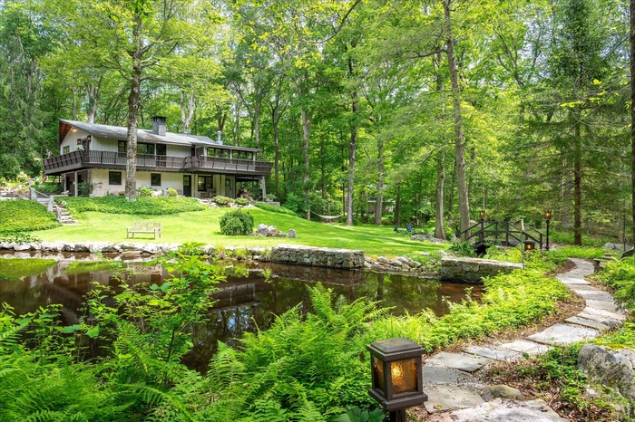 View of grassy yard with stairway, a deck, and a view of trees