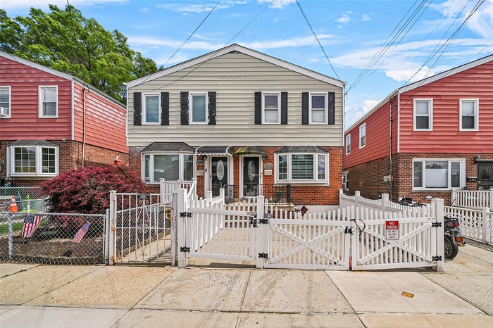 View of front of home featuring a gate, a fenced front yard, and brick siding