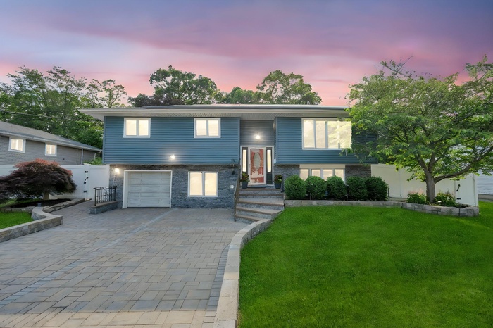 Split foyer home with decorative driveway and an attached garage