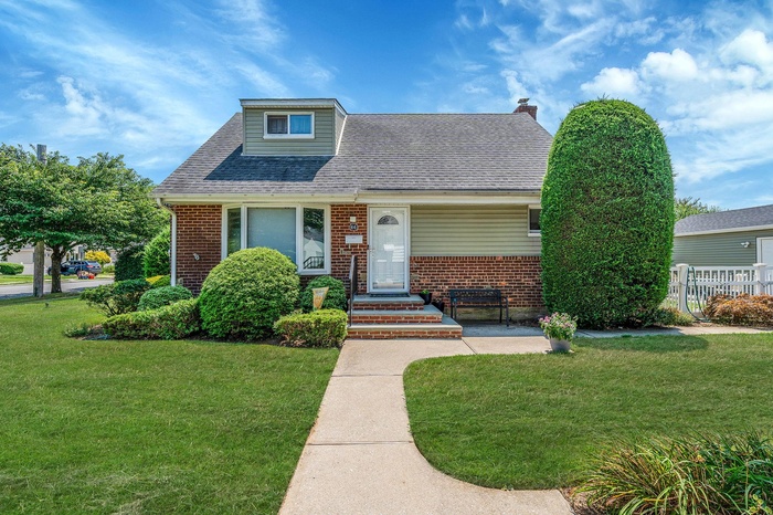Bungalow-style house with brick siding, a shingled roof, and a chimney