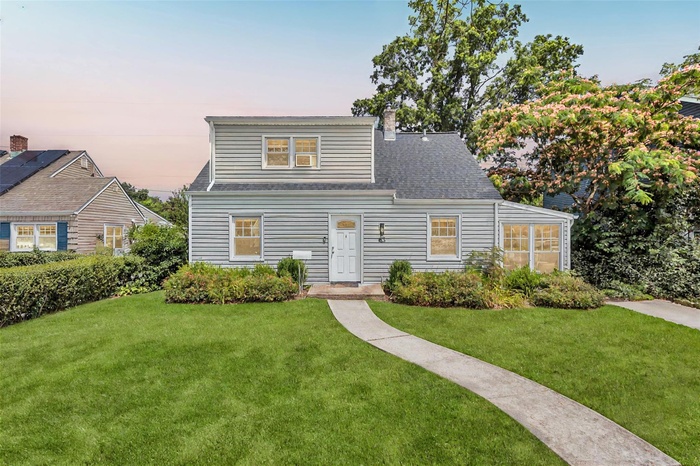 View of front of house with a yard, a chimney, and roof with shingles