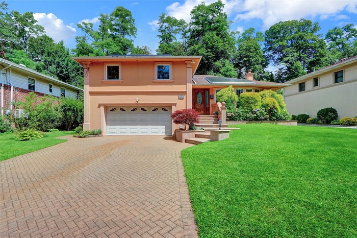 View of front of property with stucco siding, decorative driveway, a garage, a front lawn, and a chimney