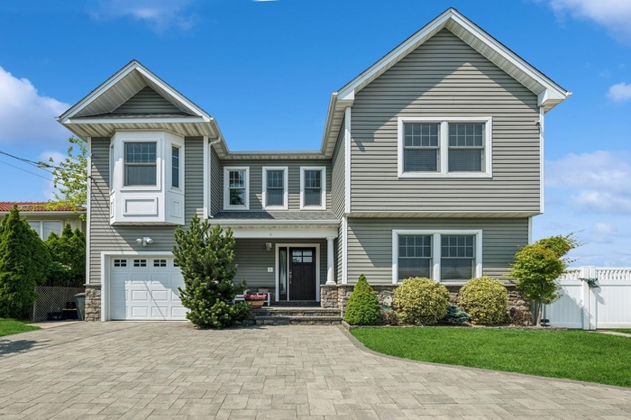 View of front of house featuring stone siding, a garage, and decorative driveway