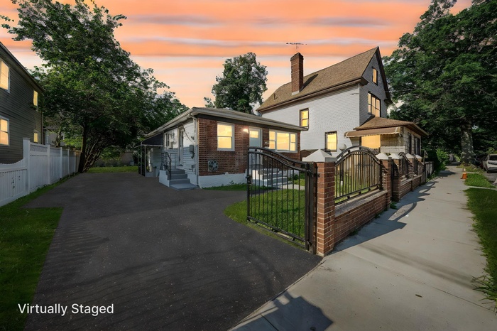 View of front of home with brick siding, a fenced front yard, a gate, and driveway