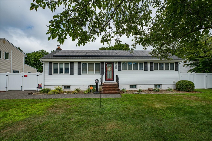 View of front of property featuring a gate, entry steps, roof mounted solar panels, a chimney, and roof with shingles