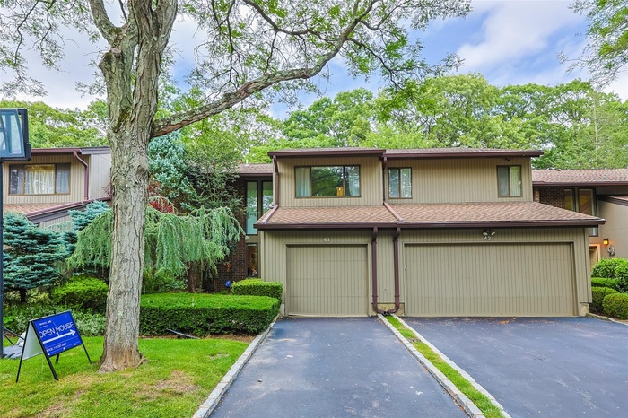 View of front facade featuring a shingled roof, an attached garage, and driveway