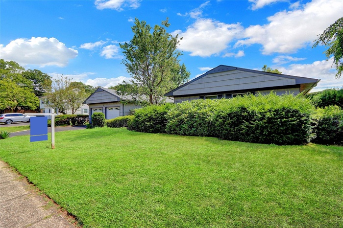 View of grassy yard featuring driveway and an attached garage