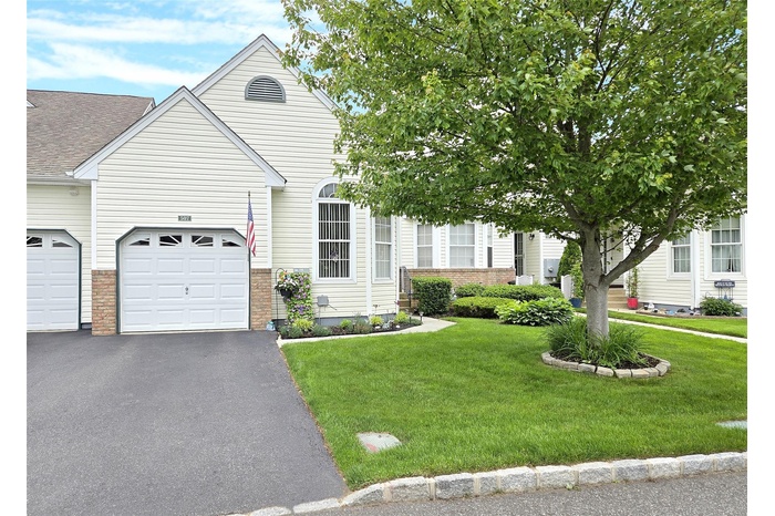 View of front of home featuring a front lawn, asphalt driveway, brick siding, and a garage