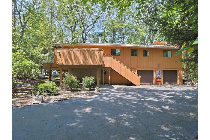 View of front facade featuring stairway, an attached garage, and driveway