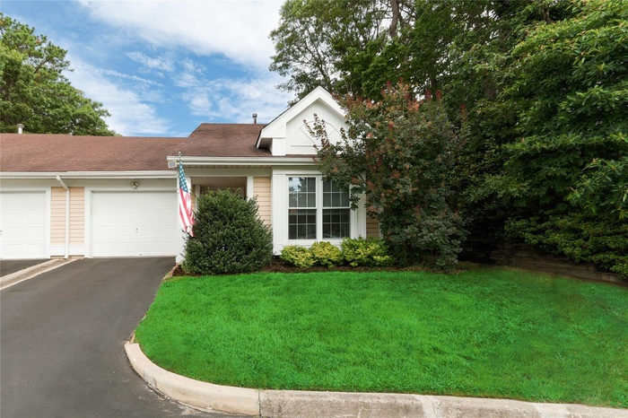 View of front of home with asphalt driveway, a front yard, and roof with shingles