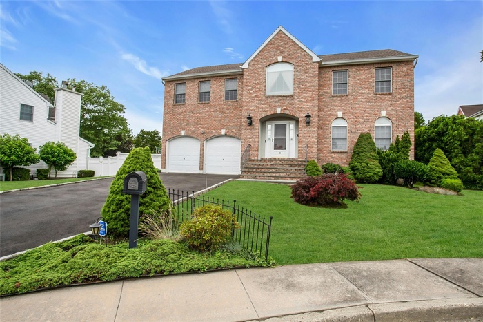 View of front of house featuring a garage, driveway, brick siding, and a shingled roof