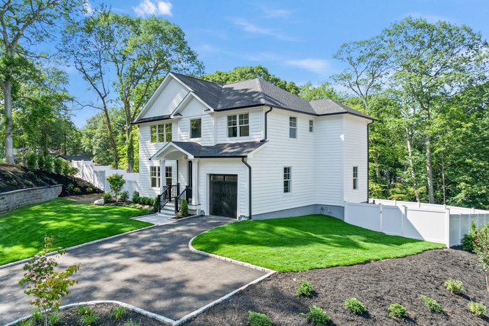 View of front facade with an attached garage, asphalt driveway, and roof with shingles