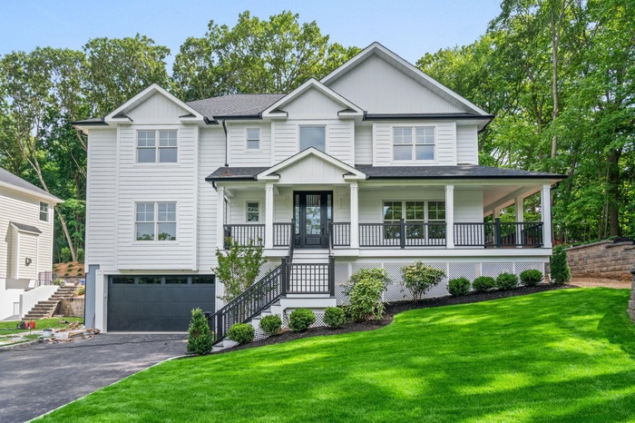 View of front of house with stairway, covered porch, an attached garage, asphalt driveway, and a front lawn