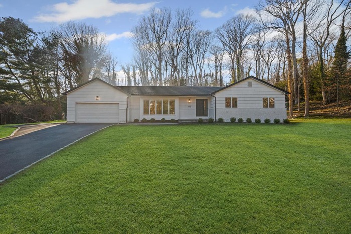 Single story home featuring driveway, an attached garage, and a front yard