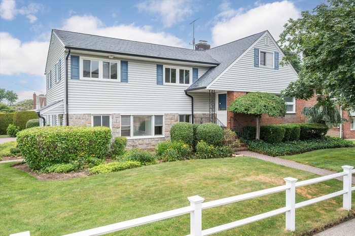 Tri-level home featuring stone siding, a chimney, and a shingled roof
