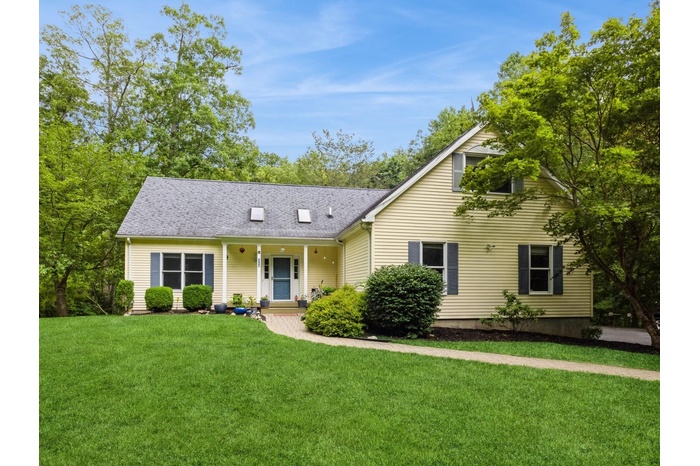 View of front of house with a front yard, roof with shingles, and covered porch