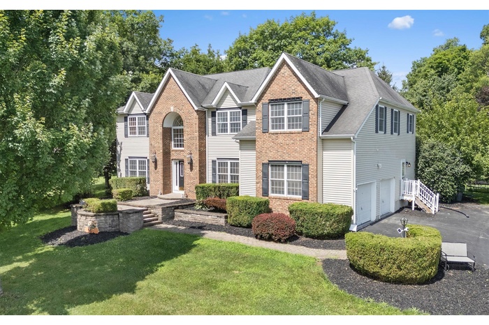 View of front of house featuring an attached garage, asphalt driveway, brick siding, and a front yard