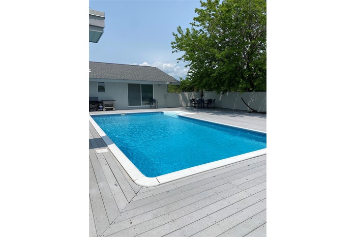 View of pool featuring outdoor dining area, a deck, and a grill