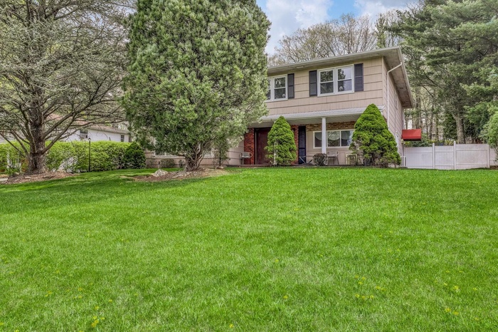 View of front facade with a front lawn and fence