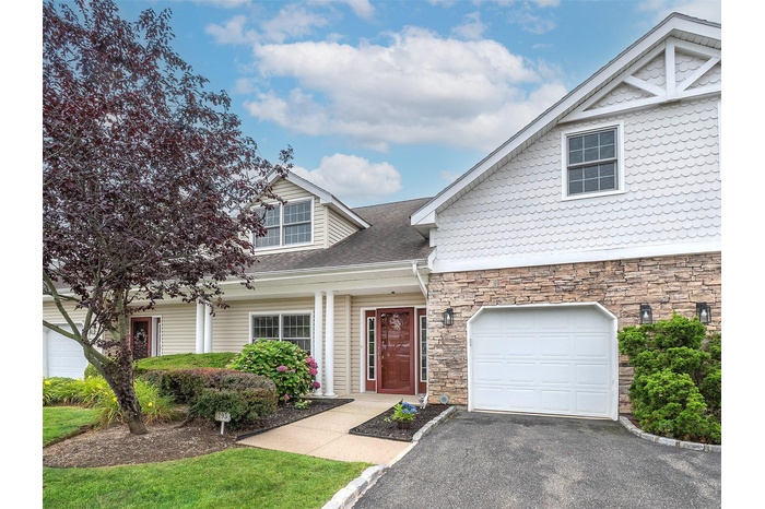 View of front of home featuring stone siding, a garage, roof with shingles, and driveway