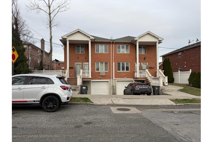 View of property with a garage, driveway, and brick siding